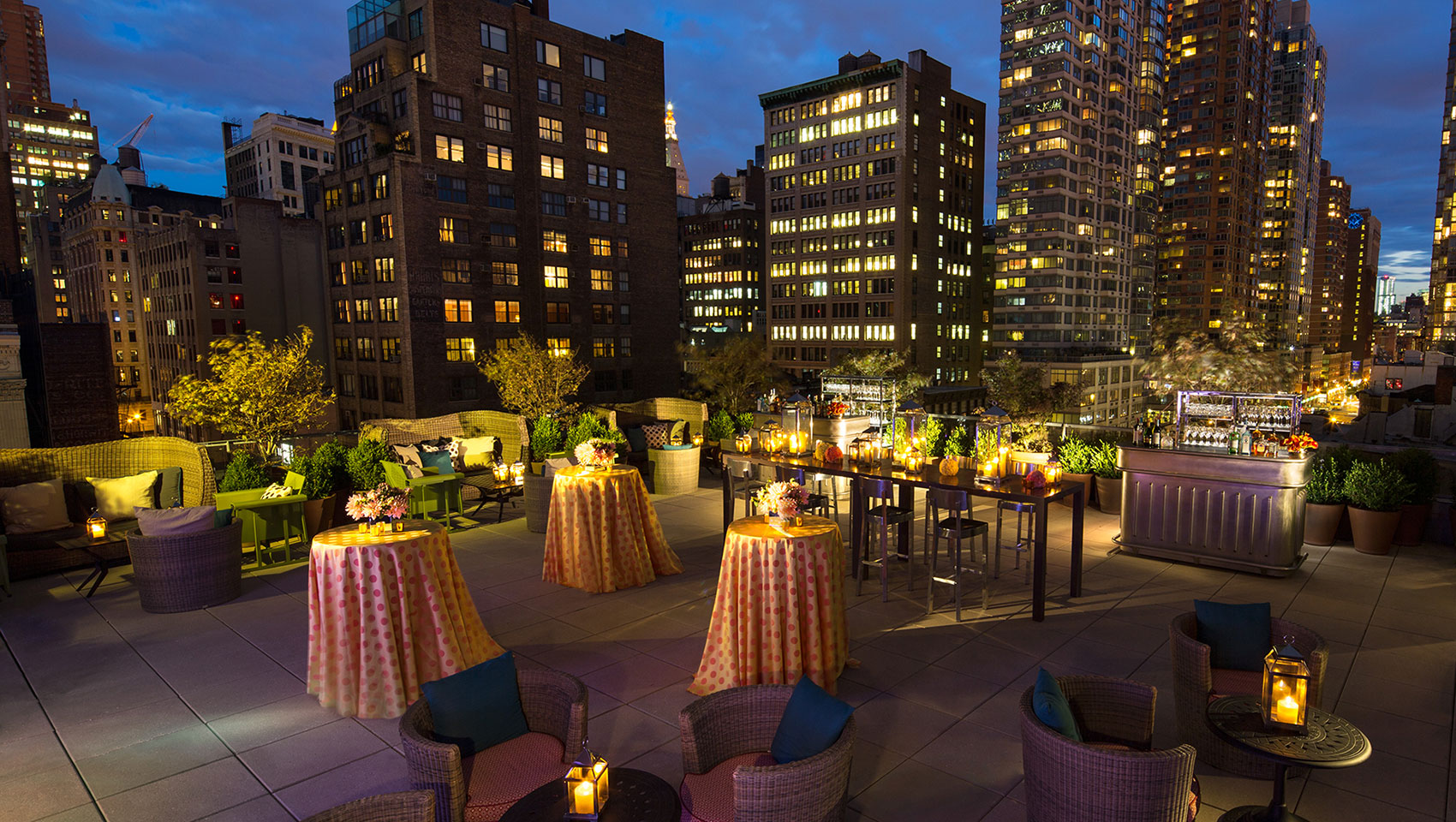 Kimpton Hotel Eventi Veranda set up for outdoor event with tables and bar against city building views at night