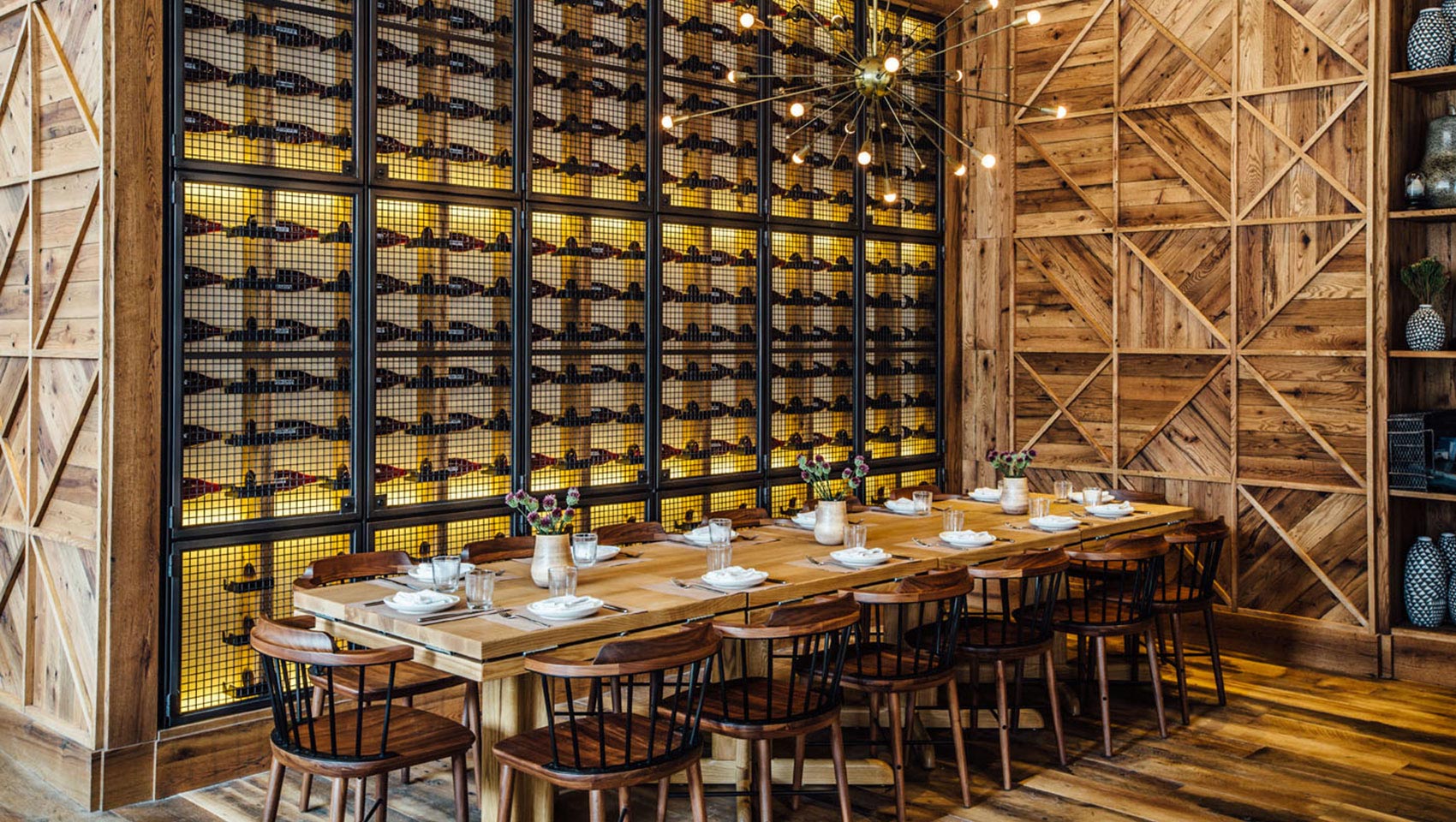 L'amico group seating with communal table, wood paneled walls, and a large wine storage area behind seating