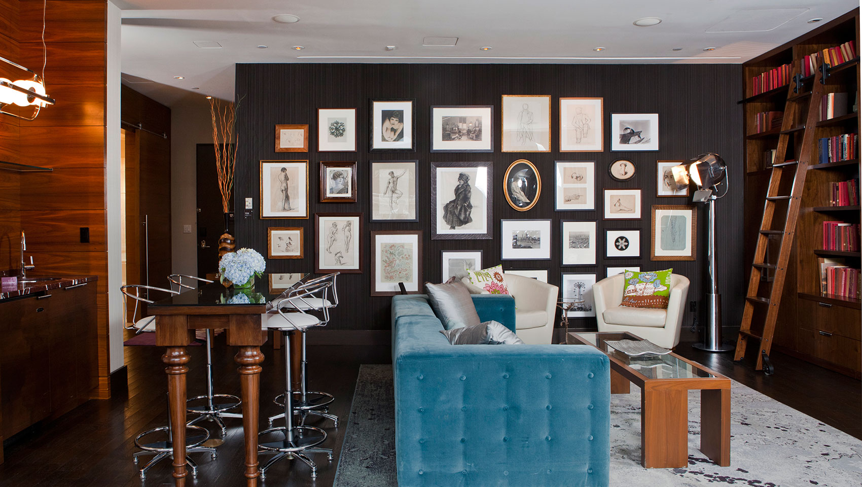 Eventi Suite living room with high table, living area, and a large wall filled with framed pictures