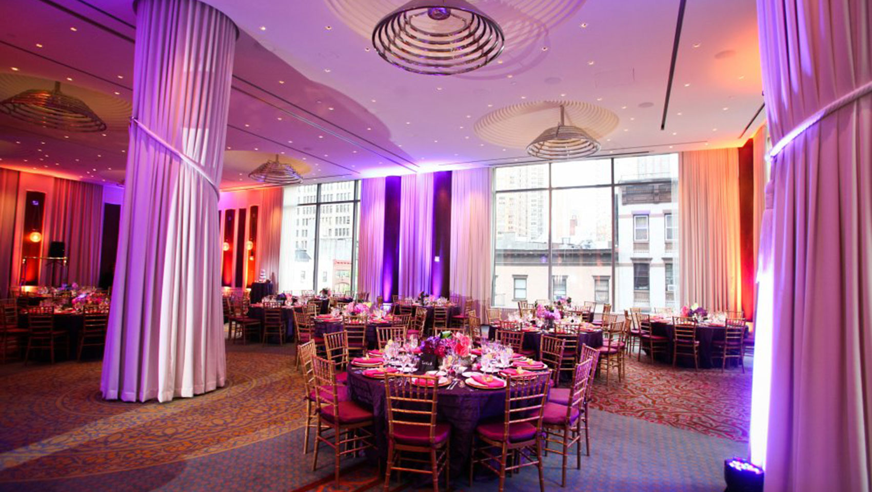 Ventana I and II with circular table next to floor-to-ceiling windows overlooking city buildings