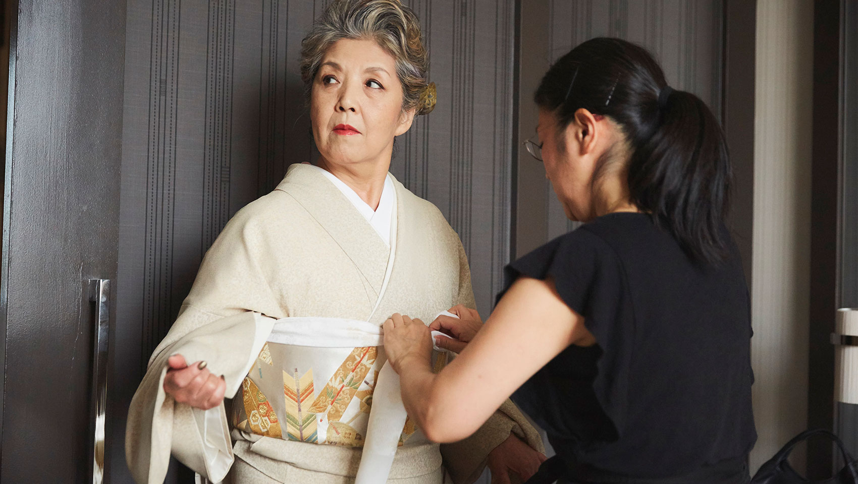 Woman helping family member in traditional attire adjust her dress