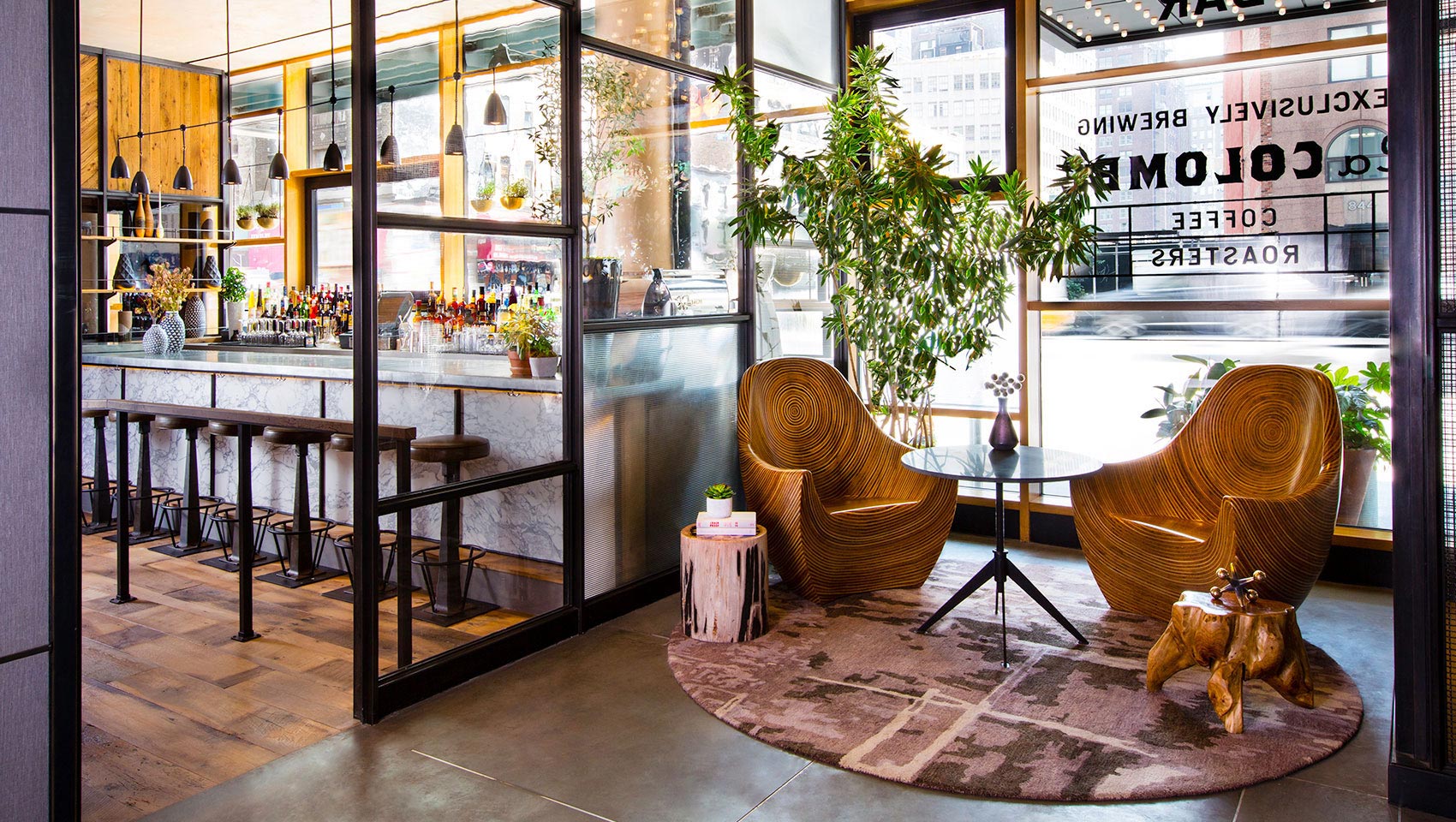 Lobby seating with wooden chairs against sunlit glass walls