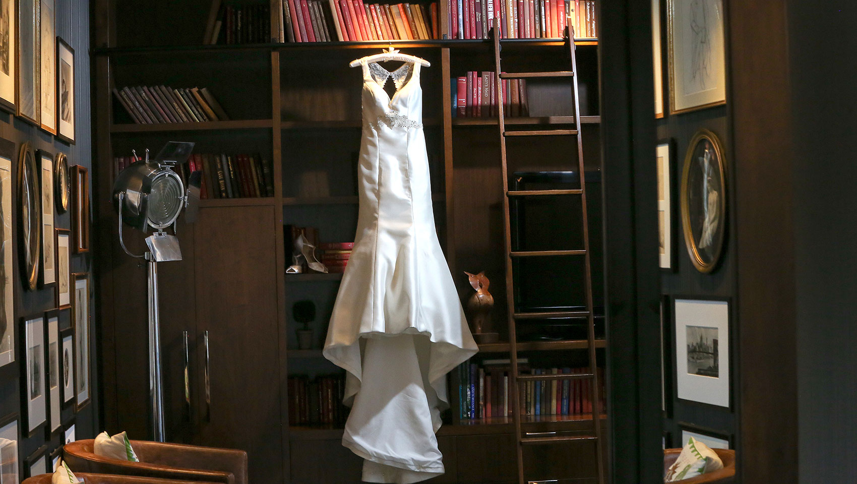 Wedding dress hanging up against bookcase