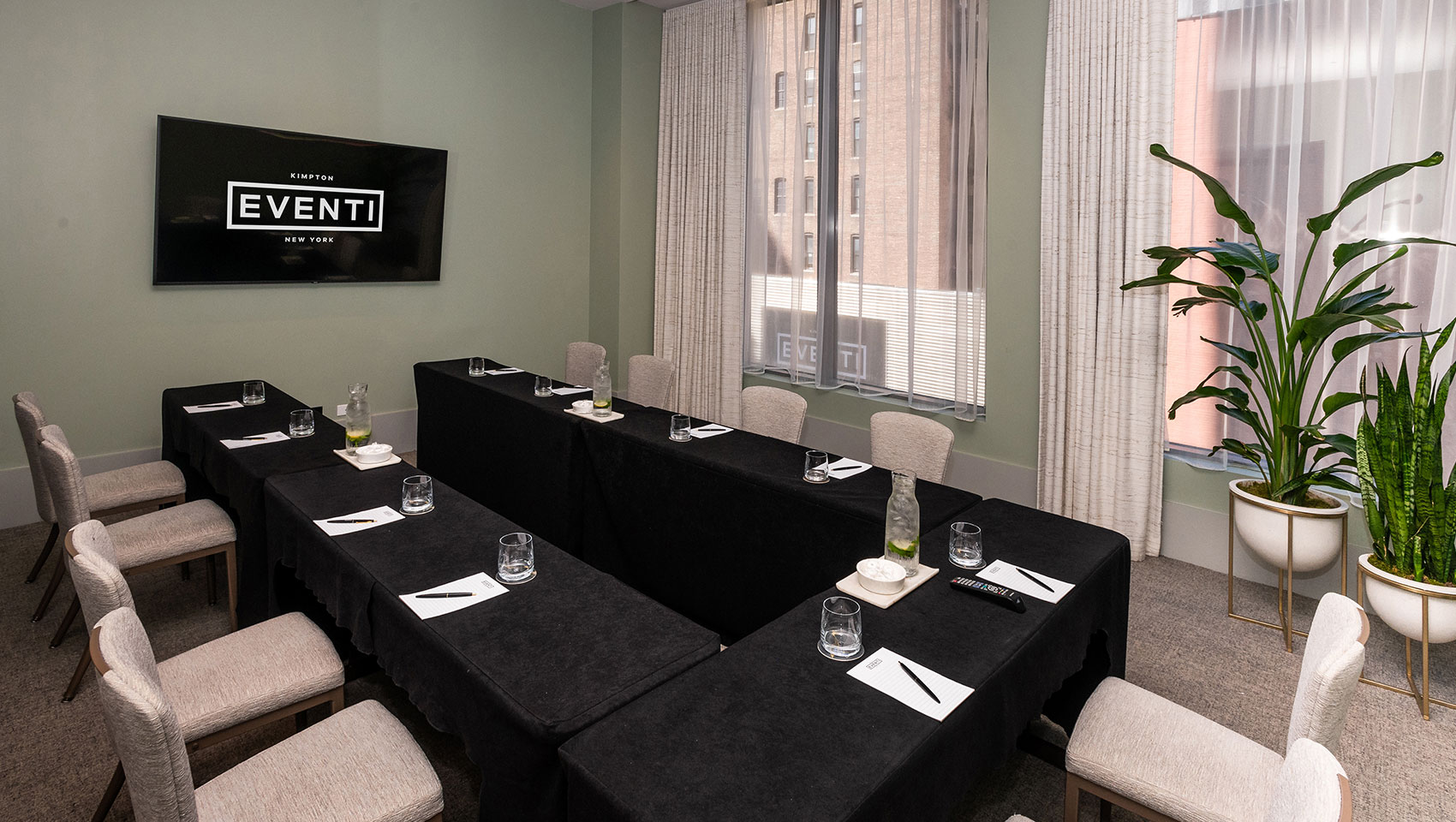 Invent II boardroom meeting with drawn curtains and meeting table with notepads, floral pieces, and glasses on table