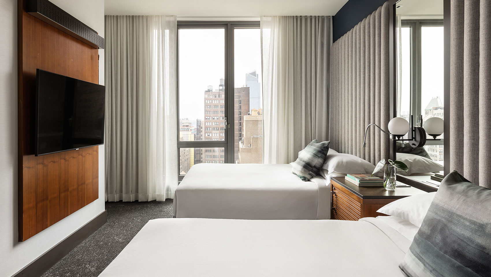 Kimpton Hotel Eventi guest room next to large window overlooking city buildings