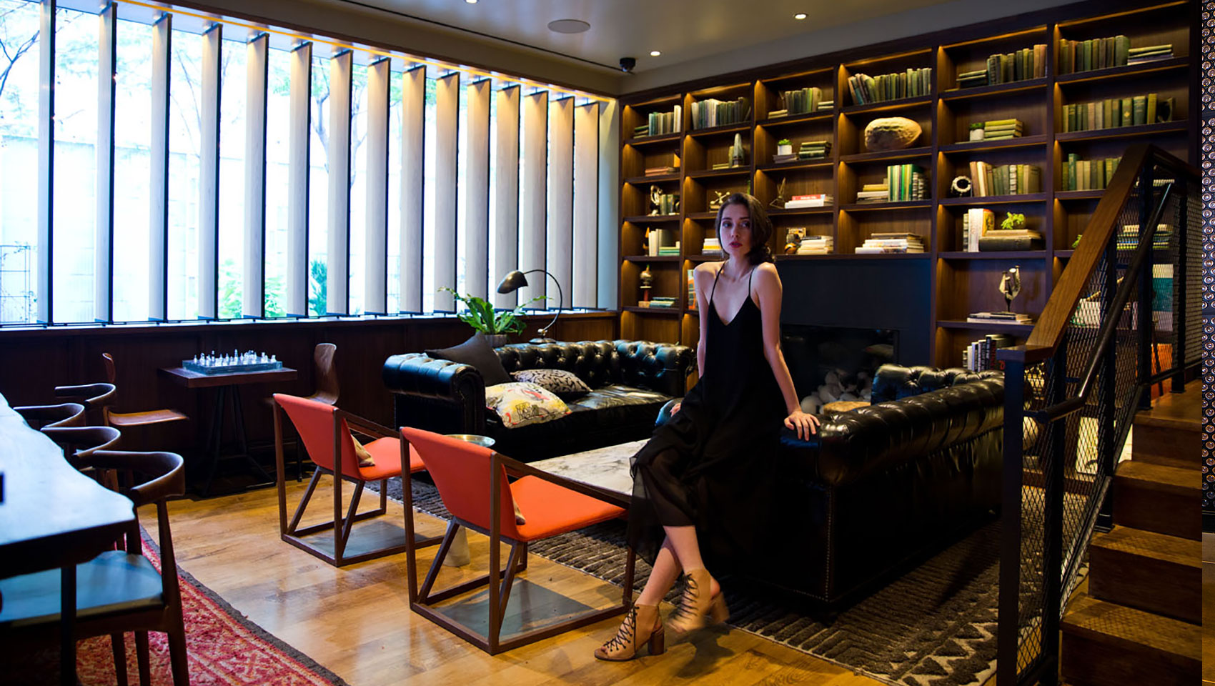 Woman leaning against leather seating in private dining area next to area with large bookshelves