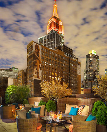 Rooftop view at night overlooking city buildings and Empire State Building