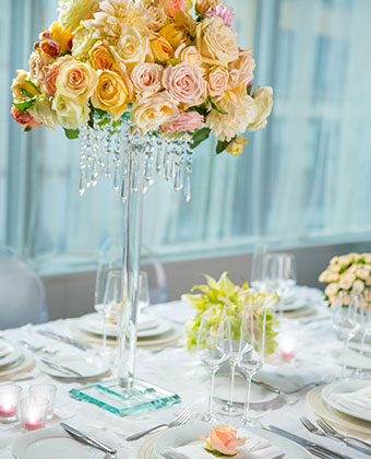 Wedding table setting with plates, candles, and a tall floral centerpiece with draping crystals