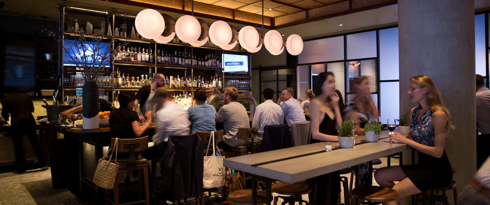 Back Bar seating with guests enjoying drinks at the bar and communal table